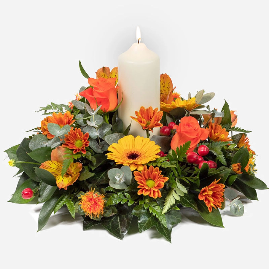 Warm glow an autumn centerpiece with orange roses yellow gerberas and a central candle