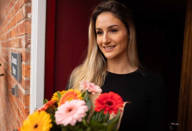 Gorgeous young lady smiling as she had bouquet of flowers just delivered.