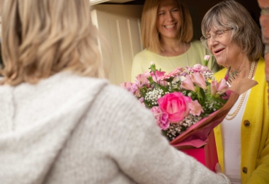 Family receive bouquet of flowers at the door. Everyone smiling